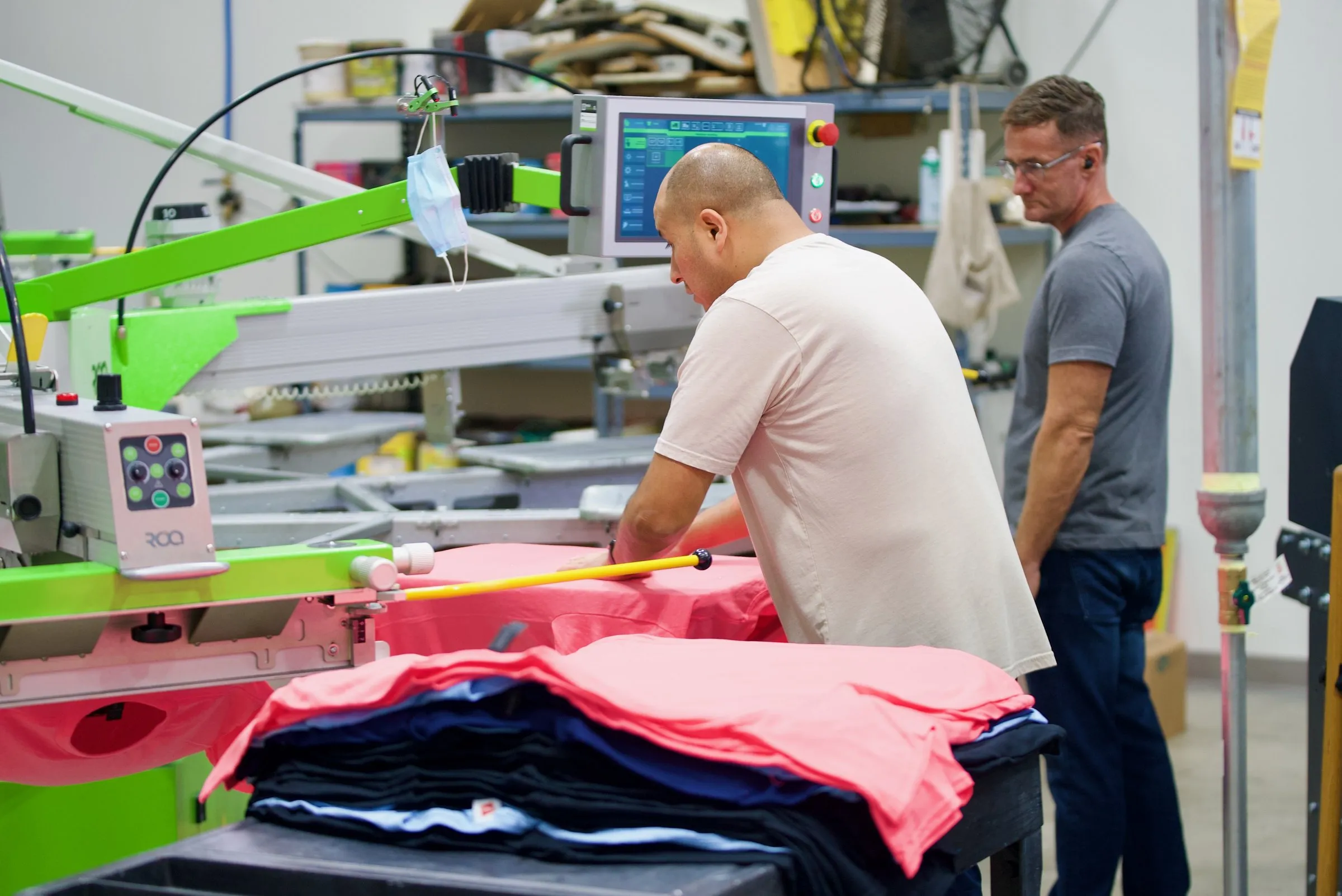 A press operator lines up pink shirts on the automatic press in our San Marcos shop