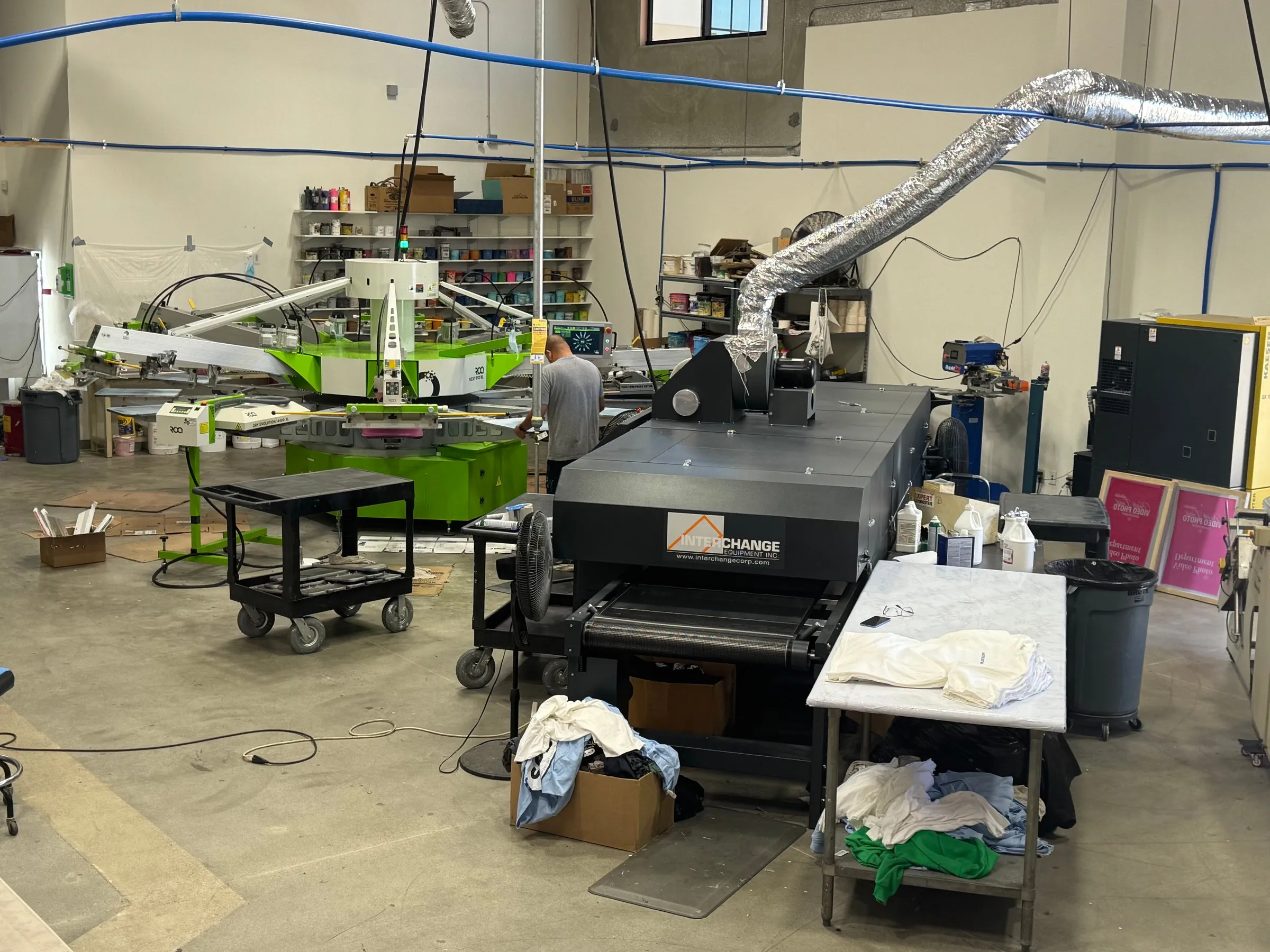 The San Marcos shop floor, with the automatic press, the dryer beside it and a printer at work