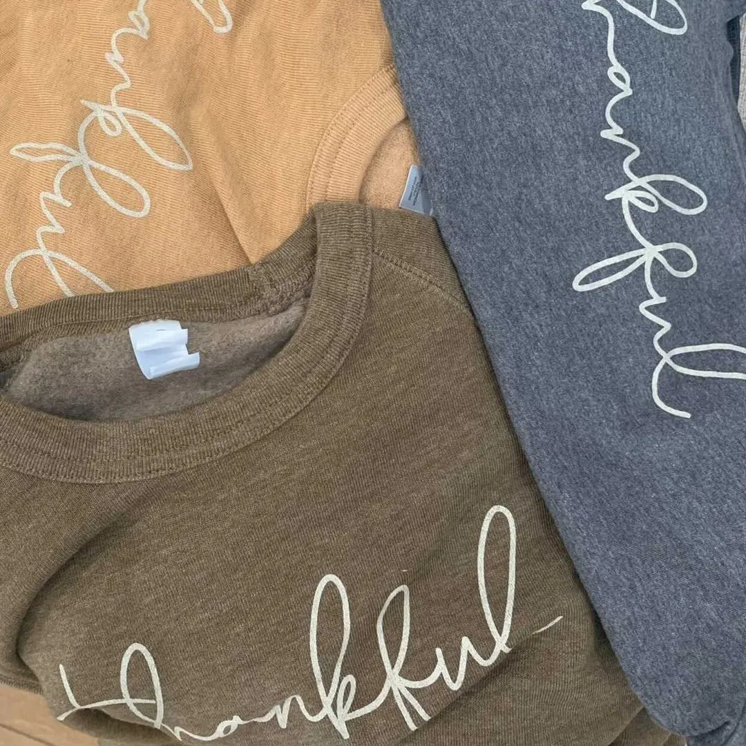 Script word prints on three heather shirts laid flat