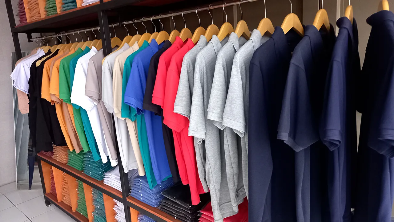 A variety of colorful t-shirts and sweatshirts displayed on hangers in a clothing store.